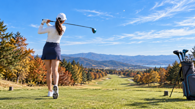 秋のゴルフ場でドライバーを振り抜く女子ゴルファーの後ろ姿